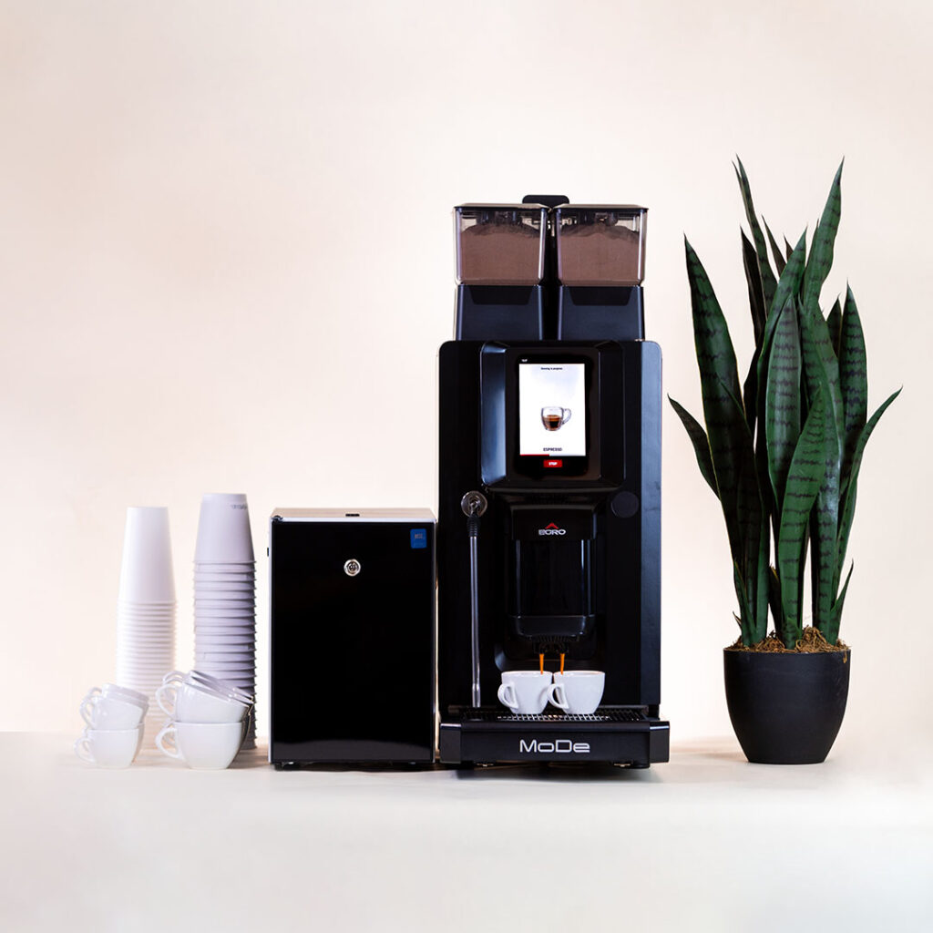 Espresso machine on a table with cups and a plant